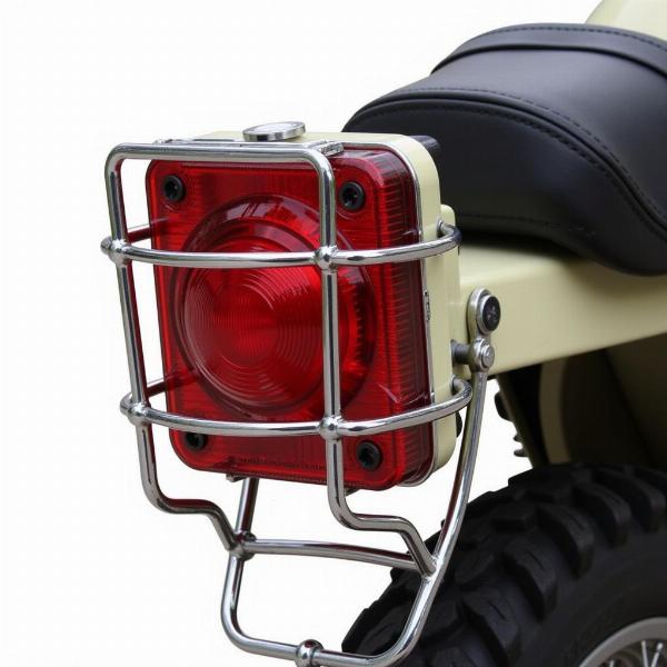 Feu arrière moto vintage scrambler de forme carrée avec grille de protection.