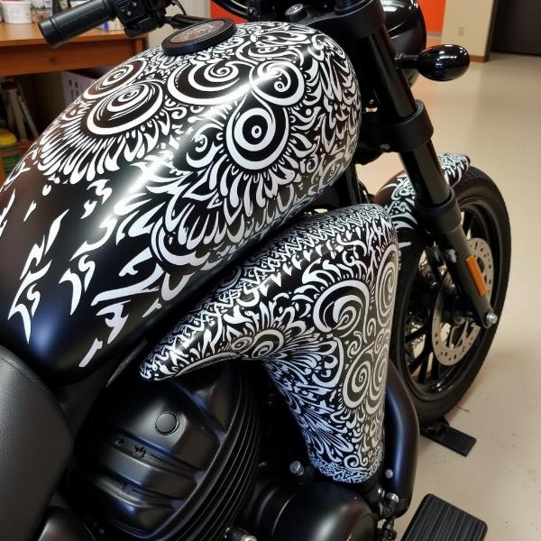 Peinture personnalisée sur moto avec des motifs tribaux complexes en noir et blanc.