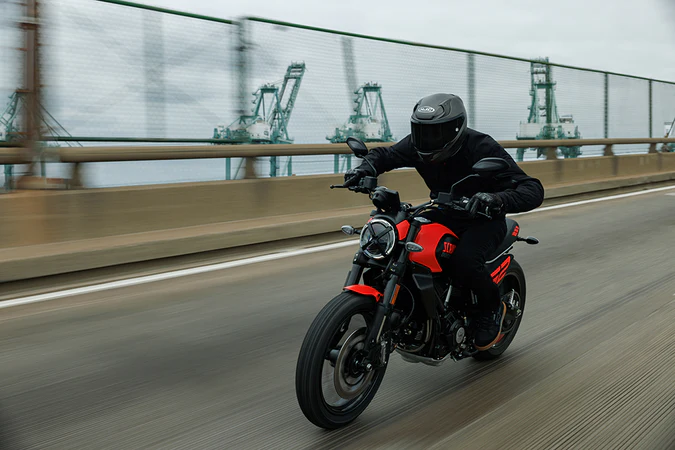 Casque HJC RPHA 12 porté par un motard sur une moto rouge sur une route