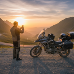 Motard photographiant sa moto au coucher du soleil sur un col de montagne