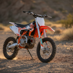 Moto tout-terrain 110cc compacte sur terrain rocheux, éclairage naturel chaleureux.