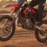 Moto KTM 85 SX rouge et noire photographiée en gros plan dynamique sur un circuit de motocross.