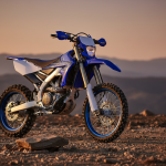 Moto enduro Yamaha WR250F en terrain accidenté, éclairage naturel, vue dynamique de trois quarts.